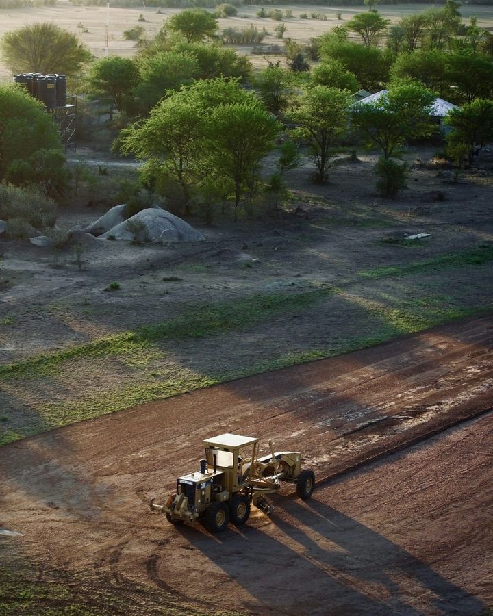 A road grader levelling red earth on a construction site